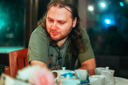 Portrait of bearded man siting in night bar and drinking teaの写真素材