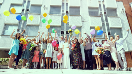 Happy young wedding guests with the bride and groom jumping with balloons after registering at the registry officeのeditorial素材