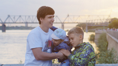 Father with his children on promenade during sunset time on beautiful sea background. Happy childhoodの写真素材