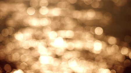 Beautiful gold abstract glittering lights bokeh background. Glistening and shimmering ocean surface at sunsetの写真素材