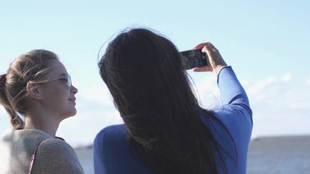 Fun Teen Girls take Selfie Vacation Photos by the sea.の写真素材