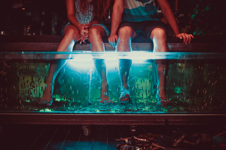 Couple enjoying with Fish Spa pedicure, foot bath using fish the eat dead skin.の写真素材
