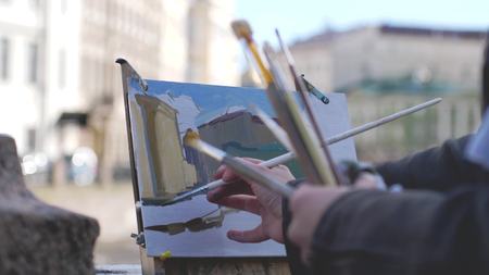Close up of street painter painting with watercolors a scene of a canal of St. Petersburgの写真素材