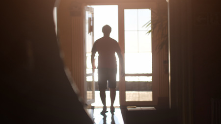 silhouette of a man walking towards the exit along the corridor to sunlight during sunsetの写真素材