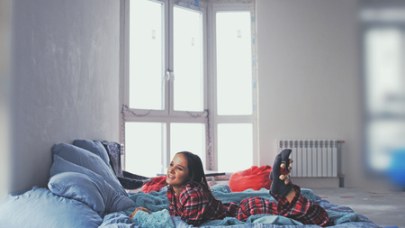 Dreamy young beautiful woman lying in bed and looks at the windowの写真素材