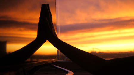 Female hand touches in the reflection of the window Silhouette Hand during amazing Sunset.の写真素材