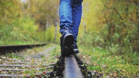 Boy walks along railway in beautiful autumn park.の写真素材