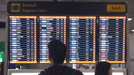 Thailand, Bangkok, 29 january 2018. Man passenger arriving and looking at flight baggage claim timetable in the airportのeditorial素材