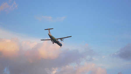 Airplane flying in cloudy sky at sunset time