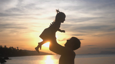 Father and happy daughter playing together at tropical beach at amazing sunsetの写真素材