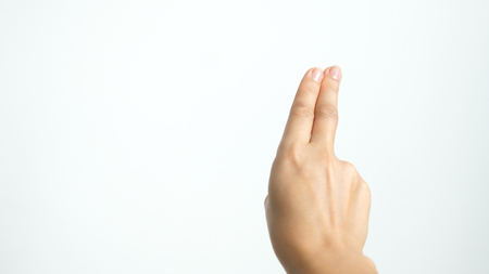 Close up of isolated female hand shows two fingers up isolated on white backgroundの写真素材