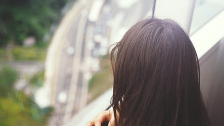 Young brunette woman looking through the window. urban city view with buildings and roads.