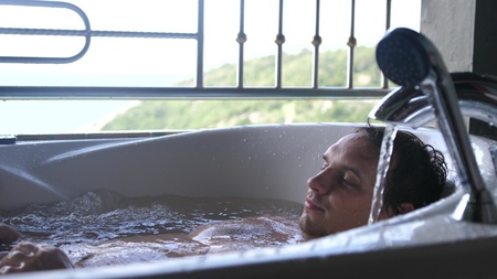 Young man relaxing in the hot tub with sea viewの写真素材