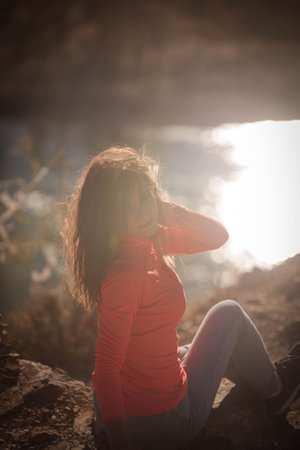 Beautiful young woman enjoys the beauty Valley along the hiking trail posing on the rock on sunny...