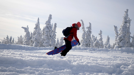 Sportive young woman carrying heavy snowboard to mountain peak on winter holidaysの写真素材