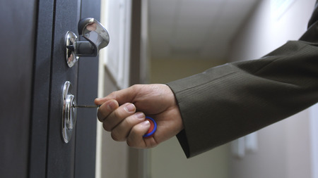 Close up of male hand unlocks a houses door with the keyの写真素材