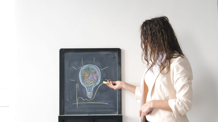 Creative young businesswoman draws light bulb on board.の写真素材