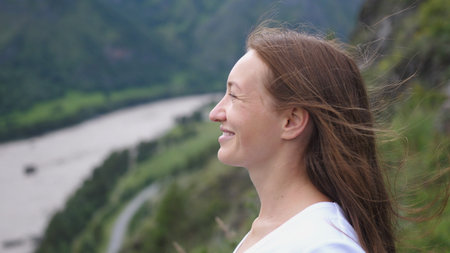 Tourist woman smiling on top of the mountain enjoying the nature