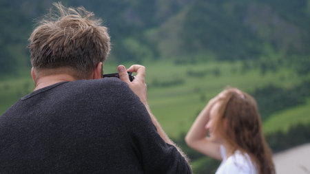 Tourists couple enjoying the nature in mountains, young man taking photos of hiking woman.の写真素材