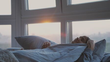 Pretty romantic brunette woman lying on bed by the windowの写真素材