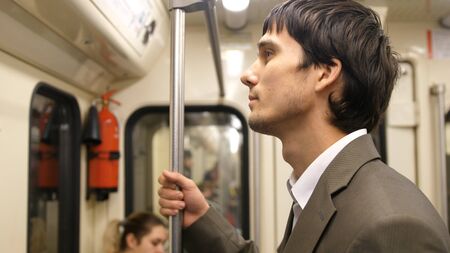 Young handsome businessman in suit standing in the subway on the way home from workの写真素材