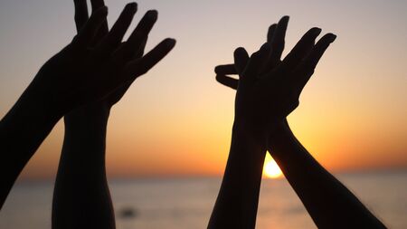 Happy family raising hands up. Hands up in the air silhouette over sunset sky.の写真素材
