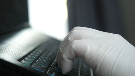 worker hand with glove working with a computer typing on a laptopの写真素材