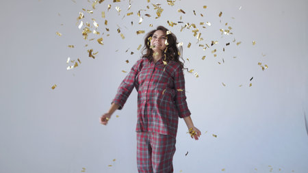 Beautiful woman dancing and throwing gold confetti.