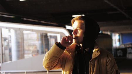 Handsome young bearded man vaping an electronic cigarette outdoors in winter. Man smoking electronic cigarette vapor.の写真素材