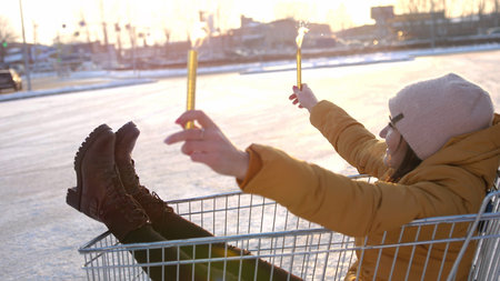 Happy young couple riding on trolley on mall parking. Sun shining on the background. slow motionの写真素材
