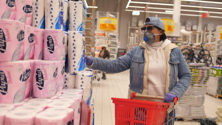 Old woman aged wearing medical Mask and gloves shopping for Toilet Paper in a Shopping Mall. Concept...