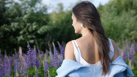 Young pretty woman among flowers violet lupins