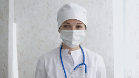 Female doctor or nurse in uniform and mask looking straight at camera. Hard work, medical, epidemic...