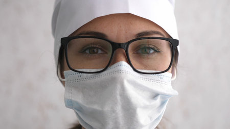 Female doctor or nurse in uniform, glasses and mask very tired after receive patients in hospital....