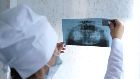 Closeup of dentist looking at dental x-ray plate.の写真素材