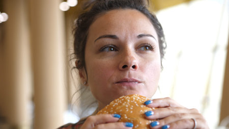 Girl eating a hamburger. close-up shot. Fast food eats. Burger in female hands.の写真素材