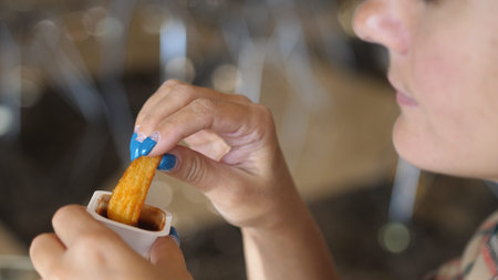 Woman eating French fries with tomato sauce, harmful and tasty fast food, close up.