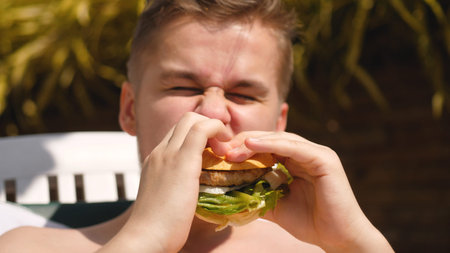 Bearded man is eating a hamburger. Junk food. unhealthy eat habits.