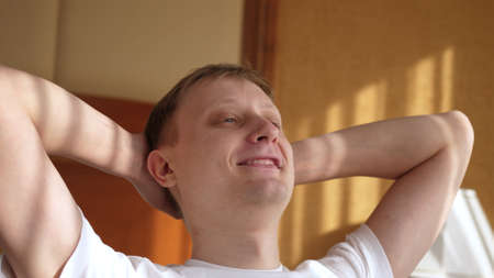 Calm happy healthy young man resting holding hand behind hand eyes closed lean on comfortable armchairの写真素材