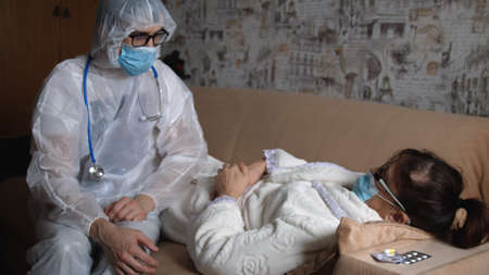 Doctor in a protective suit helping Senior old woman patient at checkup medical consultation at home, elderly grandma listen caregiver giving support, Assistance And Elderly Care Conceptの写真素材