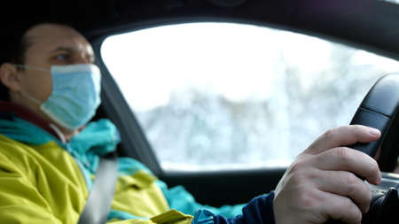 Man Traveling On Winter Automobile Road. Self Isolation On Car On virus Quarantine. Man In Face Mask Driving Car On Lockdownの写真素材