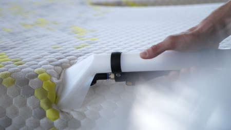 Male Worker Cleaning a mattress With Vacuum Cleaner.Professionally extraction method. Upholstered furniture. Mattress chemical cleaning.の写真素材
