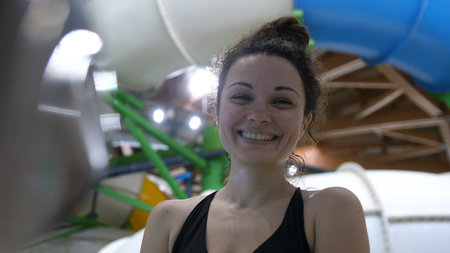 Beautiful young woman enjoys spending time in the water park smiling looking at the camera. slow...