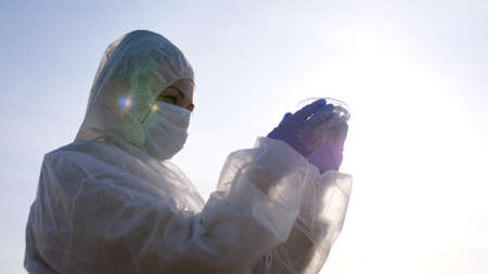 Scientist or ecology expert in protective costume with water samples probe for quality control from dirty contaminated water for scientific researchの写真素材