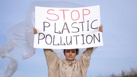 Young woman volunteer activist holding an environmental poster Stop Plastic Pollution demonstrates against protection environment, pollution natureの写真素材