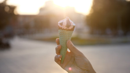 Ice Cream Melting In female Hand Outdoors in summer bright day. Food And Travel Concept.の写真素材