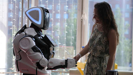 A cyborg and a young woman are cooperating each other are touching handsの写真素材