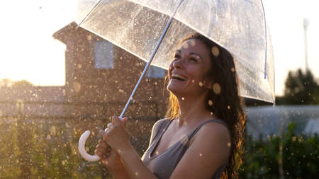 Happy young woman dancing and having fun with umbrella outdoor at sunny weatherの写真素材