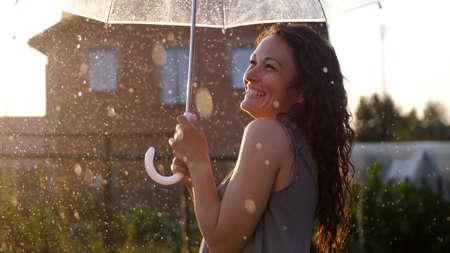 Happy young woman dancing and having fun with umbrella outdoor at sunny weatherの写真素材