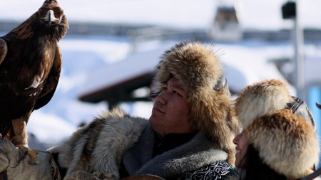 Almaty, Kazahstan - 2022. Kazakh Eagle Hunter traditional clothing, while hunting to the hare holding a golden eagle on his arm in mountain of Kazahstan and his wifeのeditorial素材